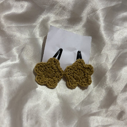 Two tan crochet hair clips on a white fabric background