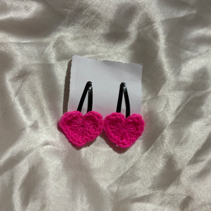 Pink heart-shaped earrings on a white card with a white fabric background