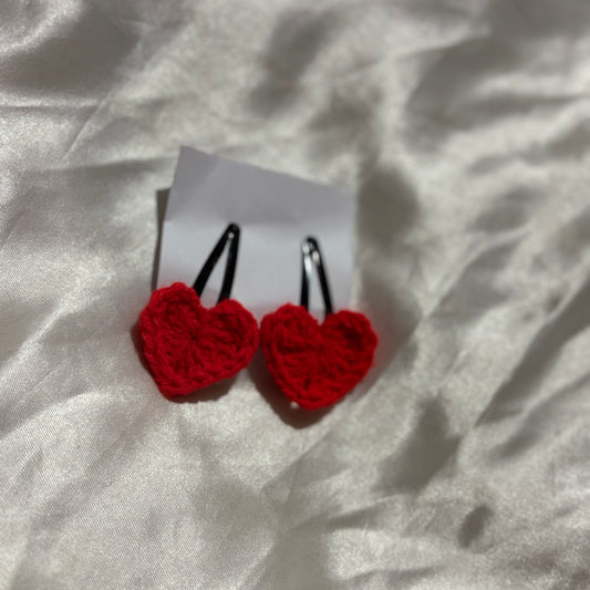 Red heart-shaped earrings on a white card with a light gray background