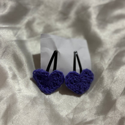 Pair of blue heart-shaped hair clips on a white card with a textured beige background