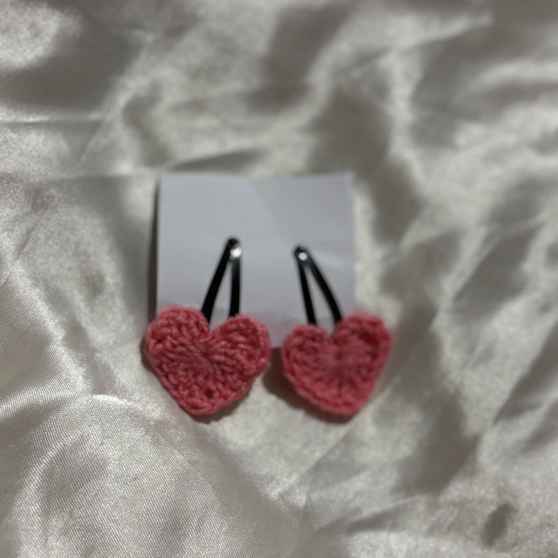Heart-shaped earrings on a white card with a textured white background
