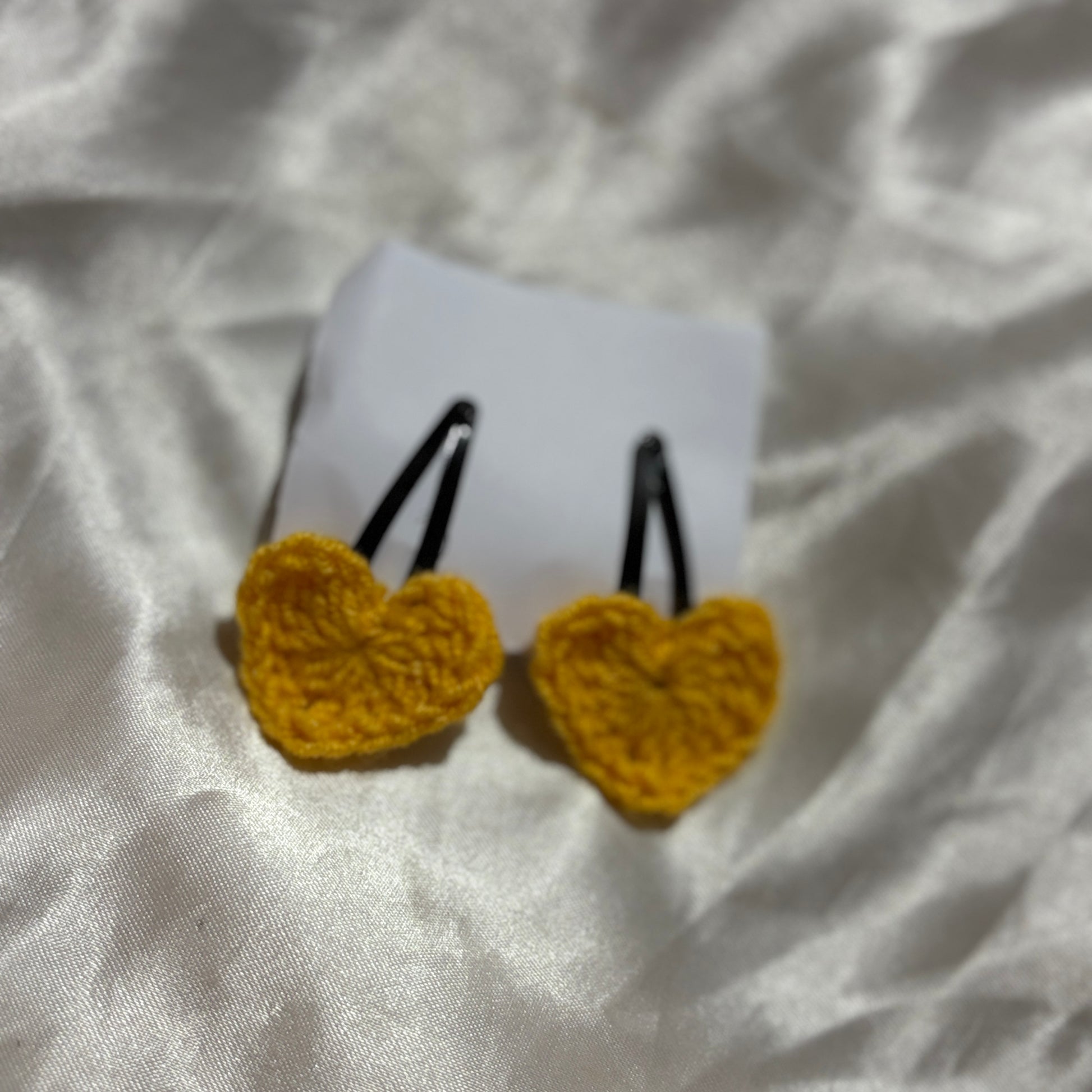 Yellow heart-shaped hair clips on a white fabric background