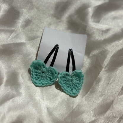 Two turquoise butterfly-shaped hair clips on a white card with a light fabric background
