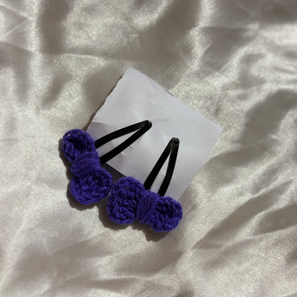 Two purple hair clips on a white card with a textured white background