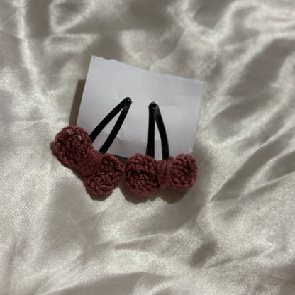 Two brown crochet hair clips on a white card with a white fabric background