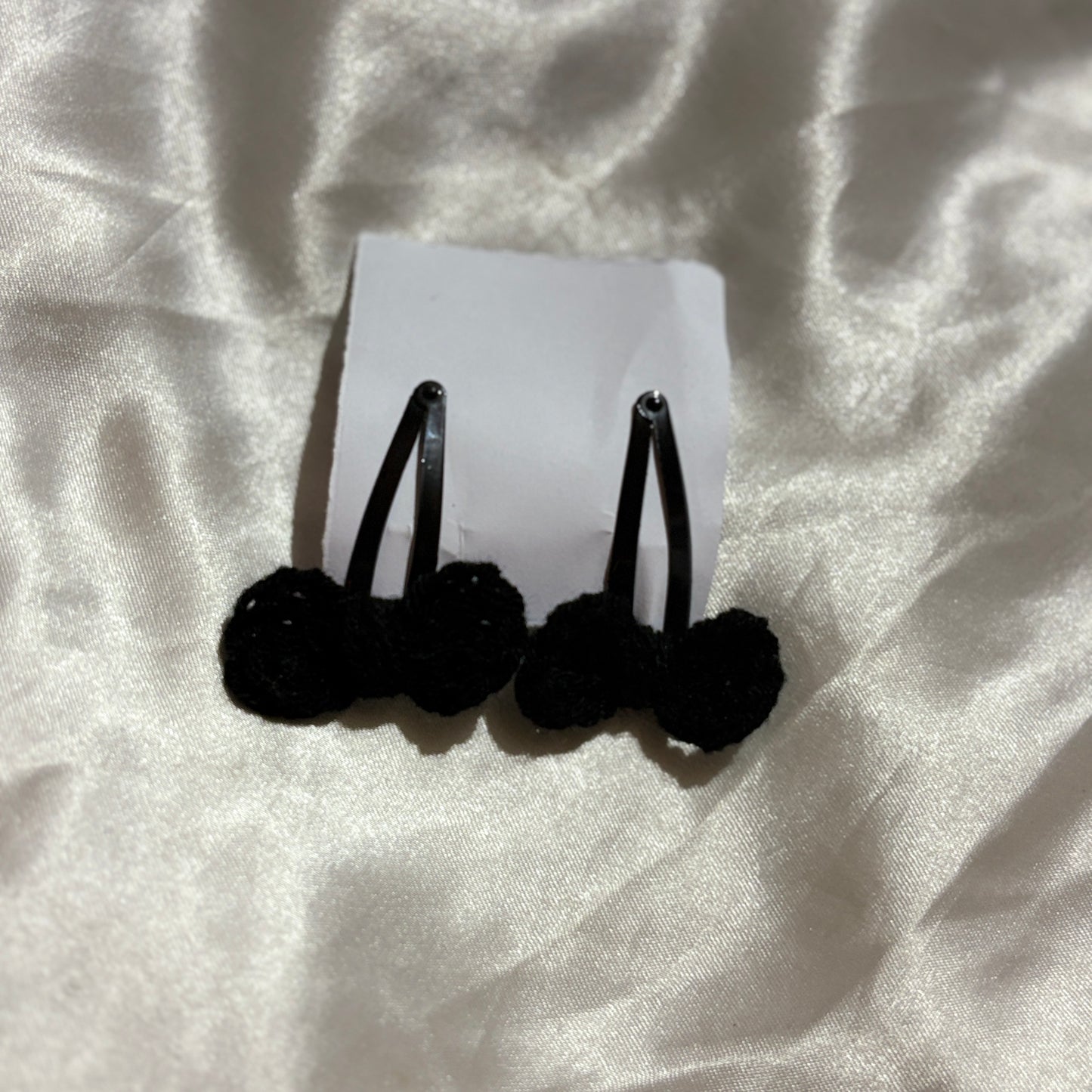 Black hair ties on a white card against a textured white background