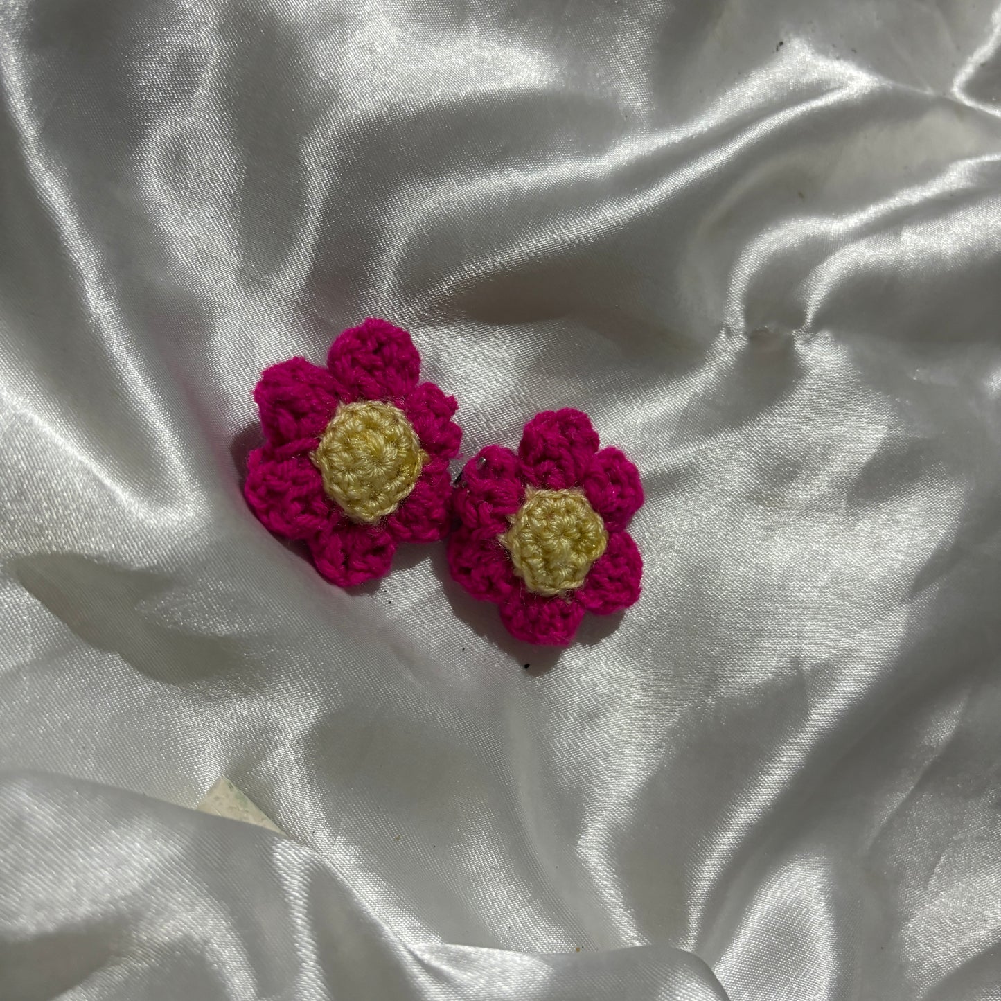 Crocheted flower clips on a textured white fabric background