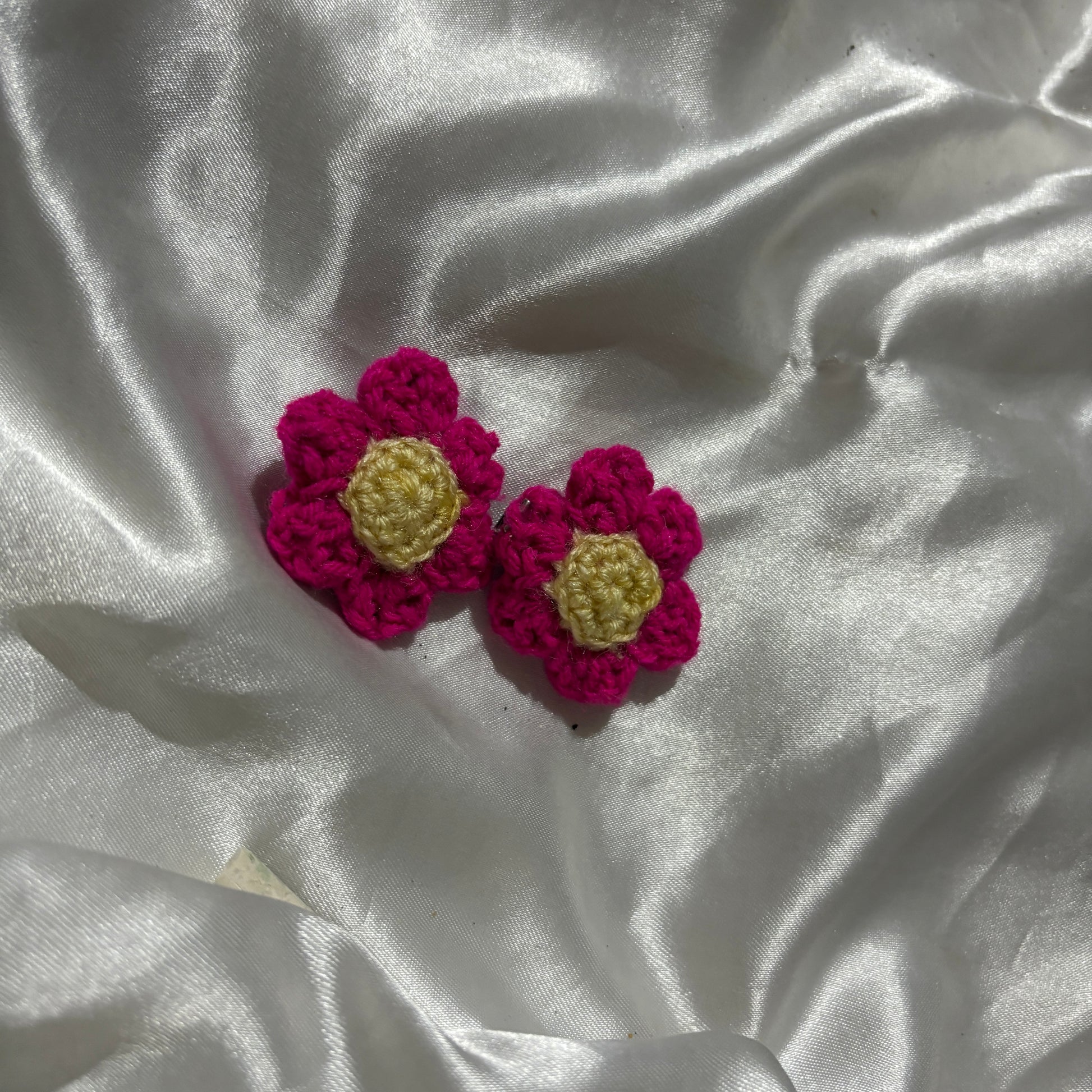 Crocheted flower clips on a textured white fabric background