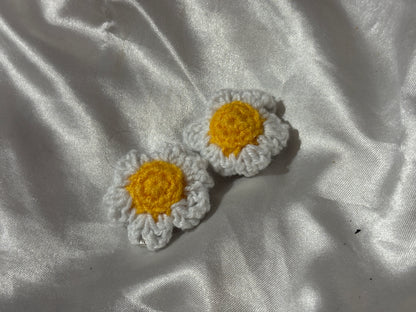 Two crocheted flower clips on a textured white fabric background