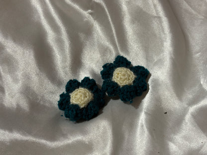 Two crocheted flower clips on a white fabric background