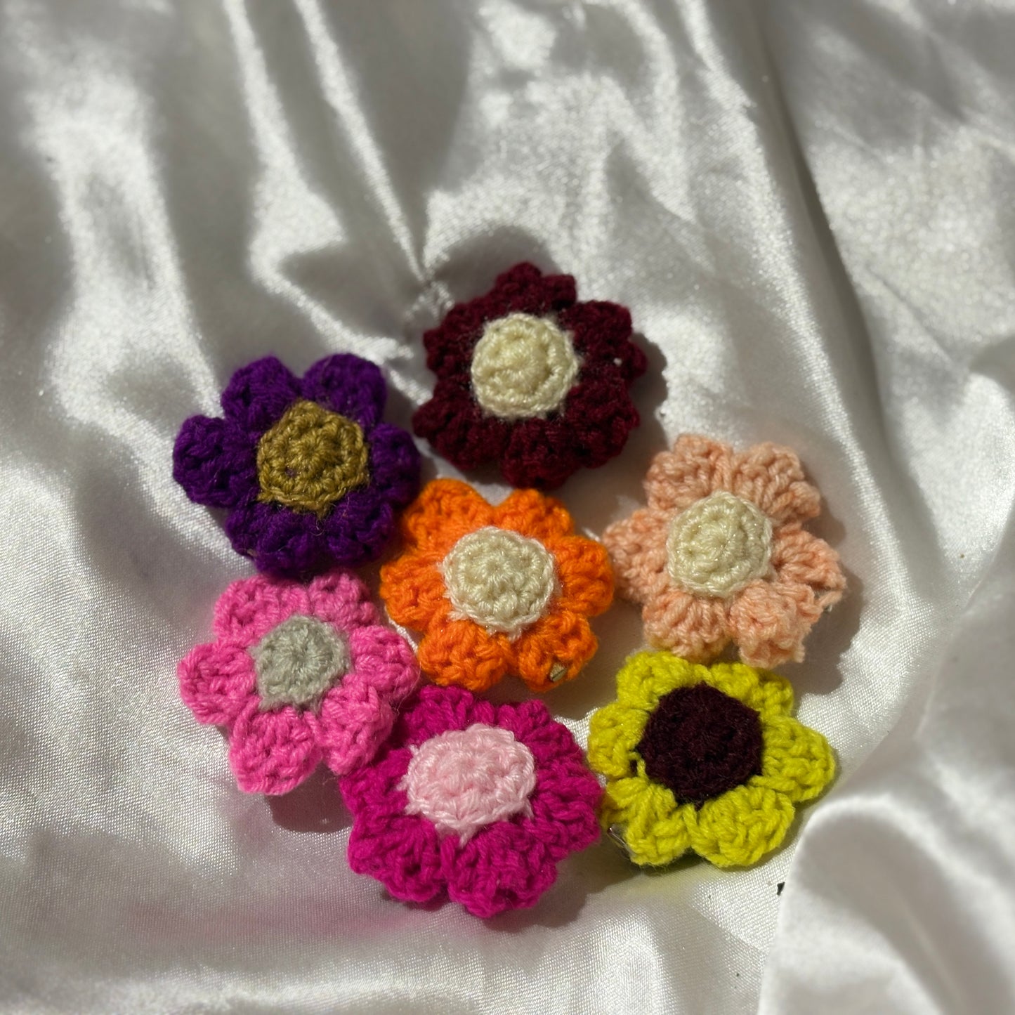 Colorful crocheted flowers on a white fabric background