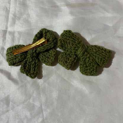 Green crocheted hair clips on a white fabric background