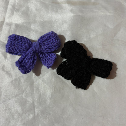 Purple and black crochet hair accessories on a white fabric background
