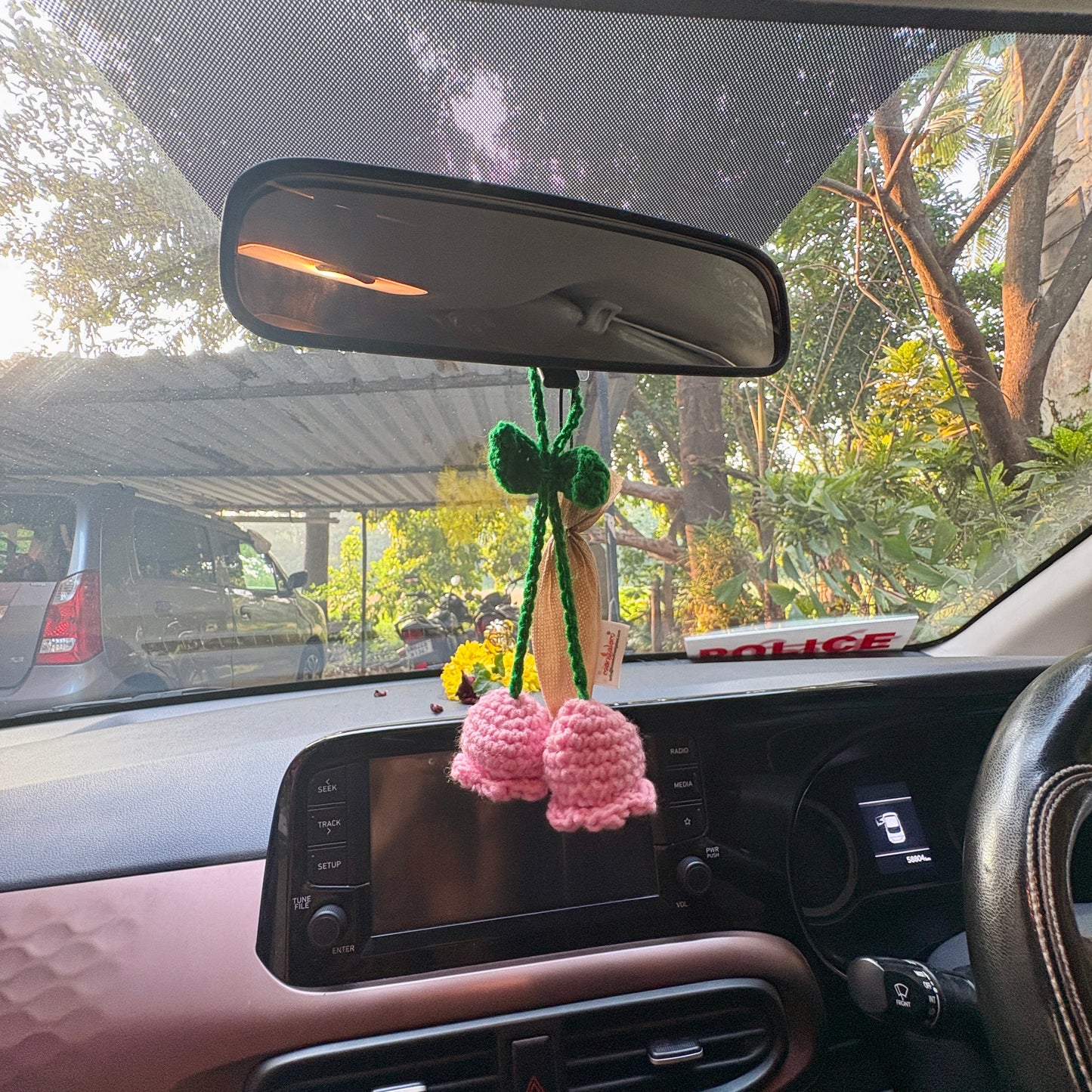 Crocheted flower decoration hanging from a car's rearview mirror