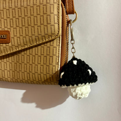 Black and white mushroom keychain attached to a beige patterned handbag.