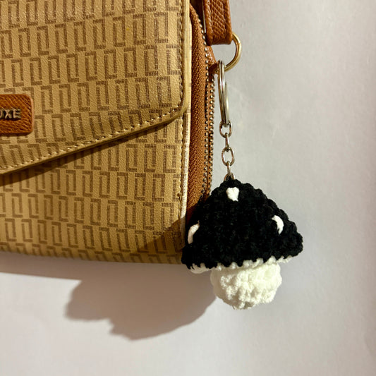 Black and white mushroom keychain attached to a beige patterned handbag.